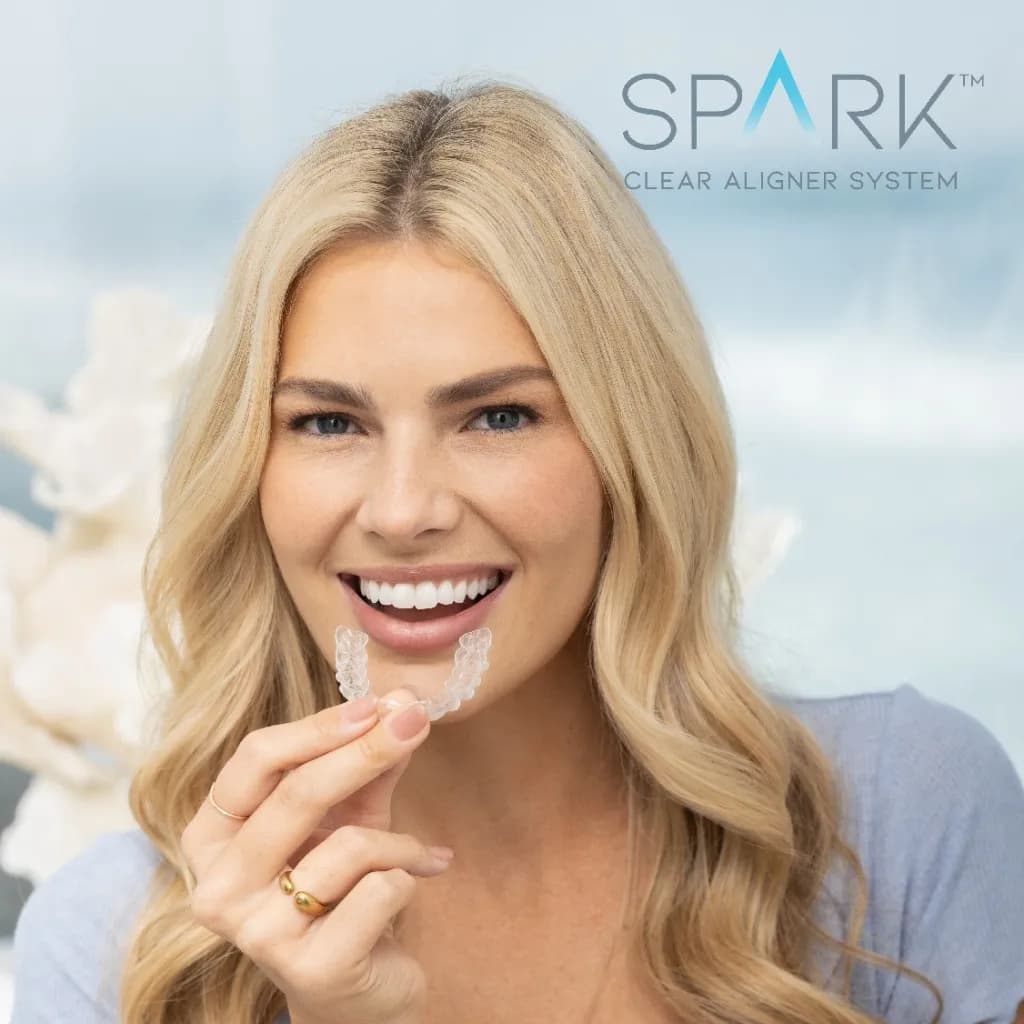 Smiling woman holding Spark clear aligners prescribed by Innova Smiles in Marlborough, MA